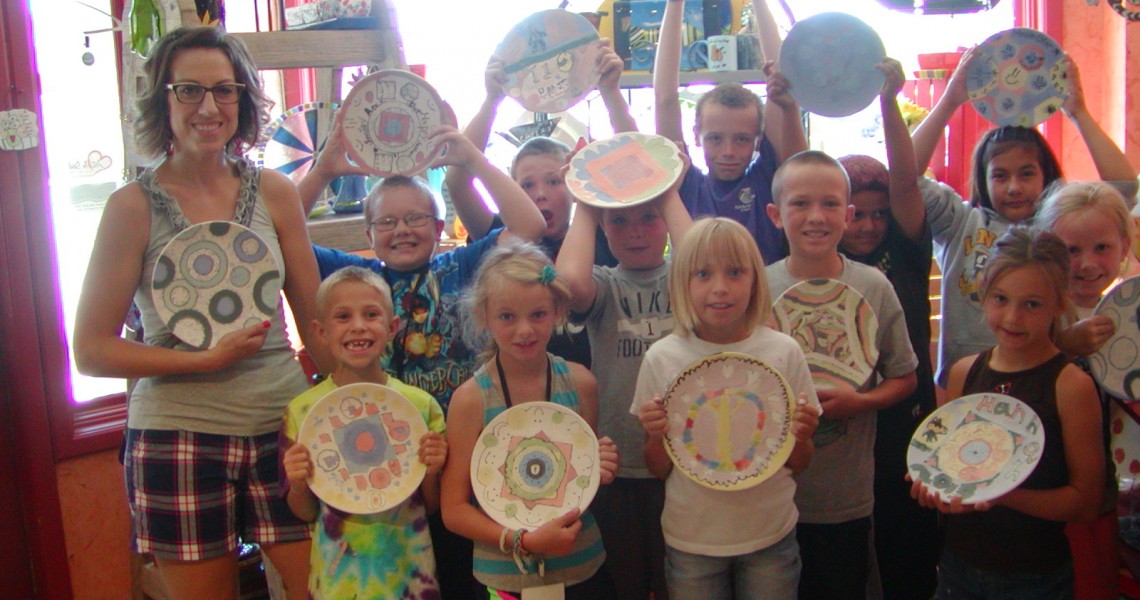 Summer camp group posing with hand painted plates during summer activity.