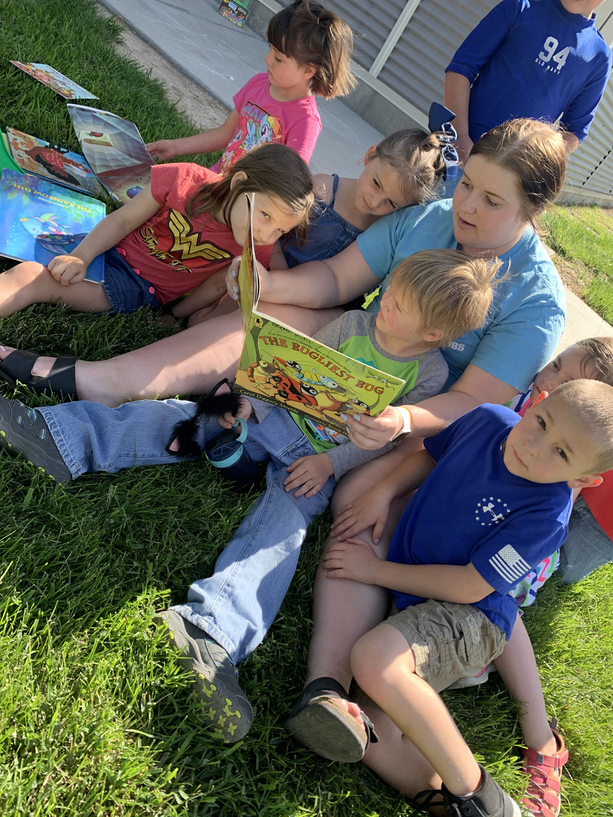 Group reading a book outside during summer activity in Twin Falls, ID.